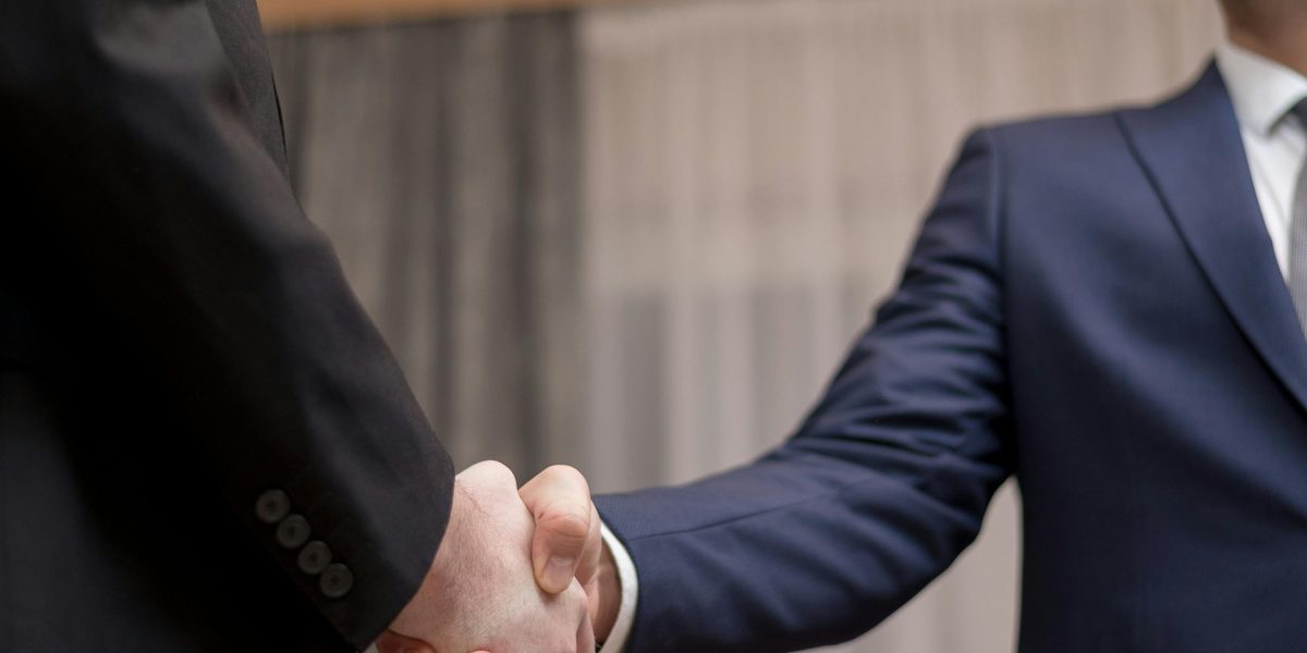 Two professionals shake hands after a successful meeting, representing partnerships and deal-making in the industry.