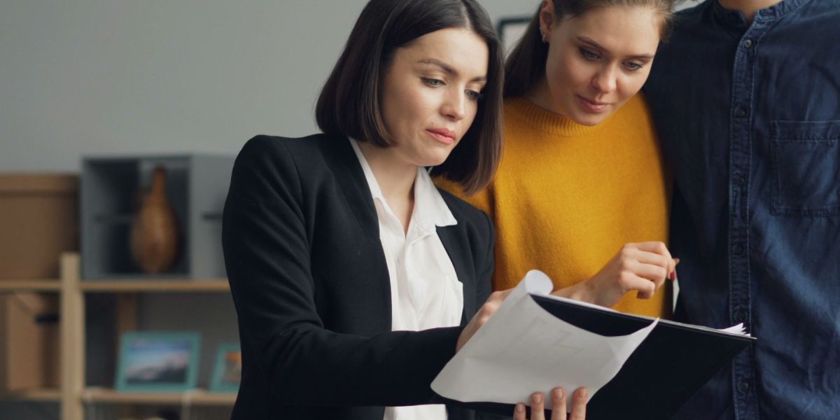 Illustrates the detailed work of a real estate agent guiding a client through crucial property documents.