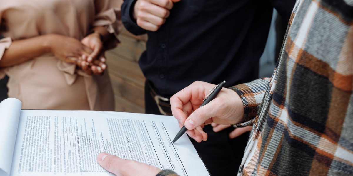 Individuals in a professional setting, focused on reviewing and signing an important legal document.